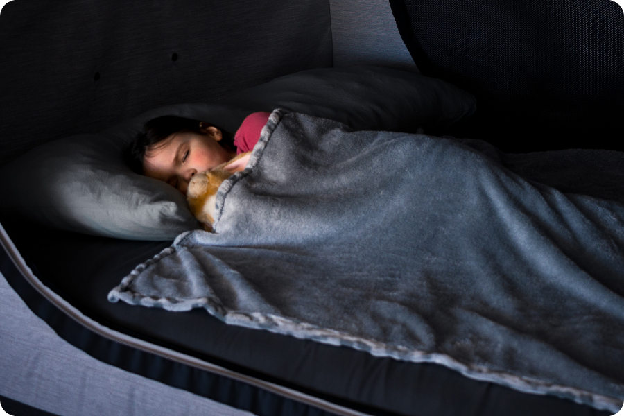 Kiddo sleeping in the Cubby Bed with a blanket and toy