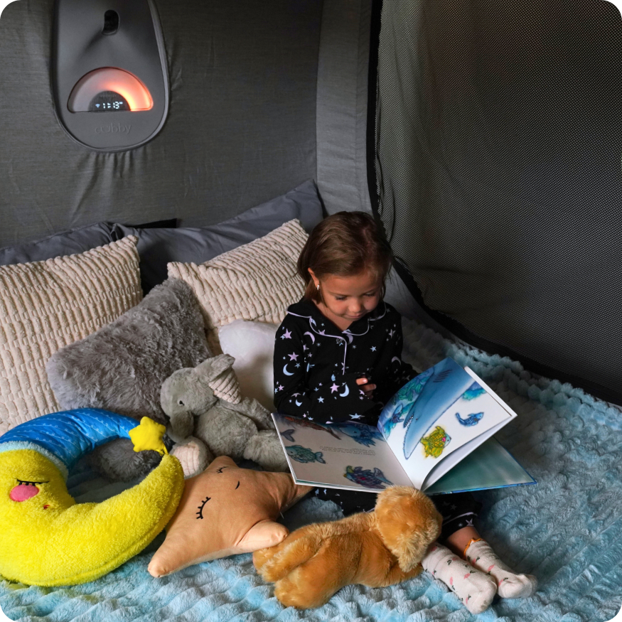 Child reading a book in a Cubby Bed with plush toys around
